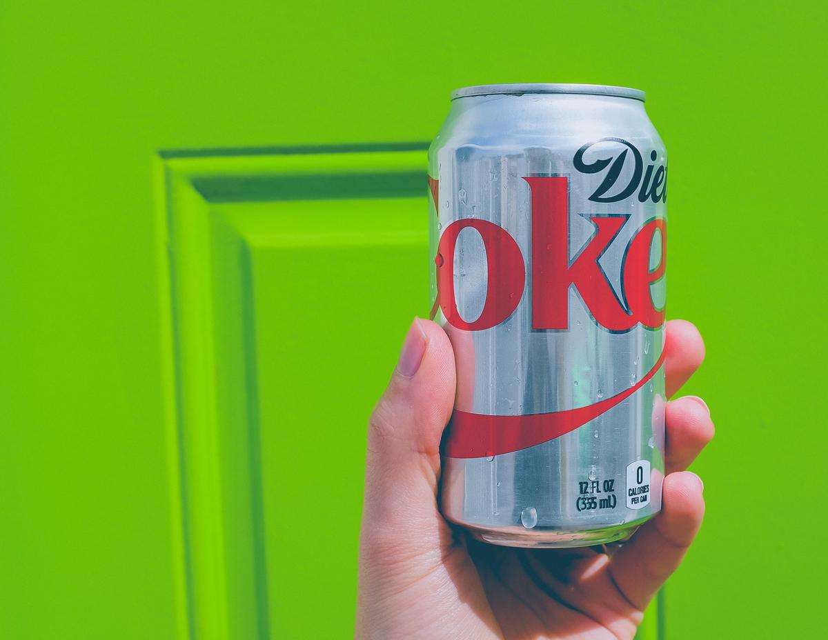 Taylor Swift holding a Diet Coke can with a smile on her face.