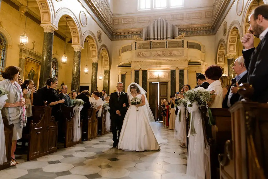 A bride in a white dress walking down a flower-decorated aisle with guests sitting in decorated chairs on either side.