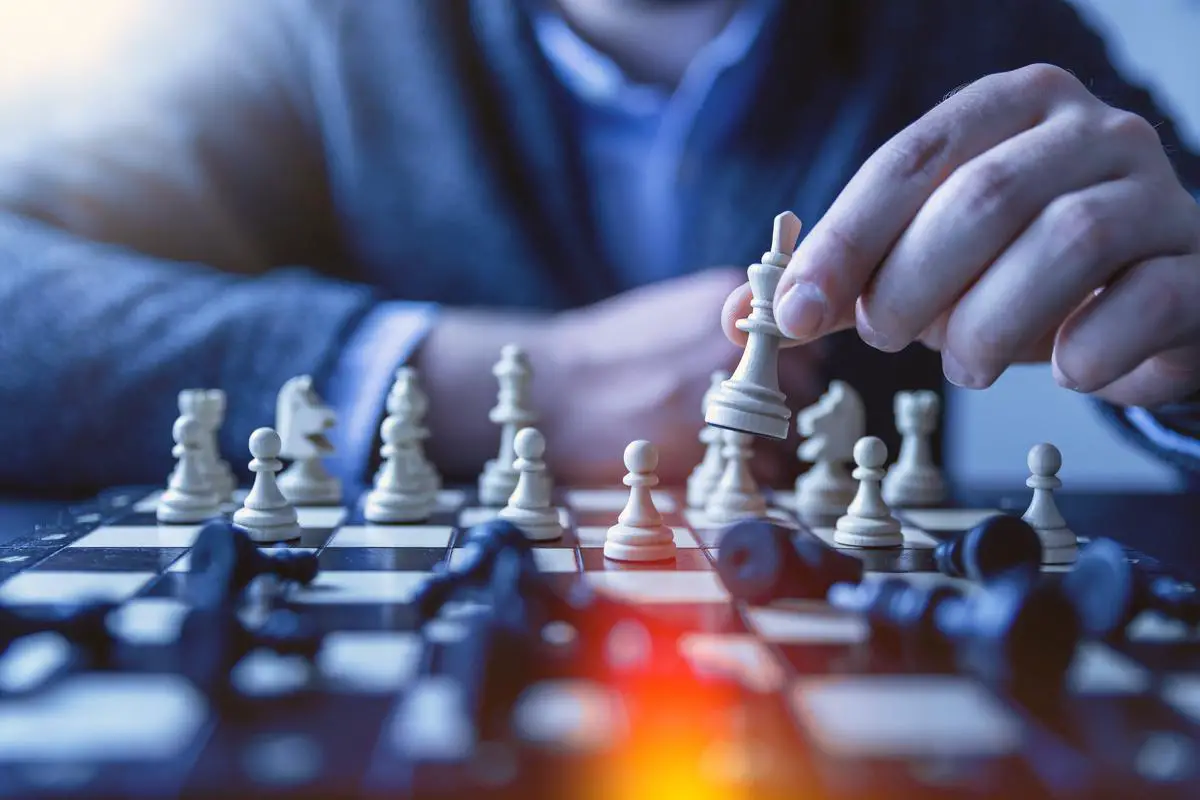 A chess coach pointing to a chessboard with a student next to him, ready to learn.