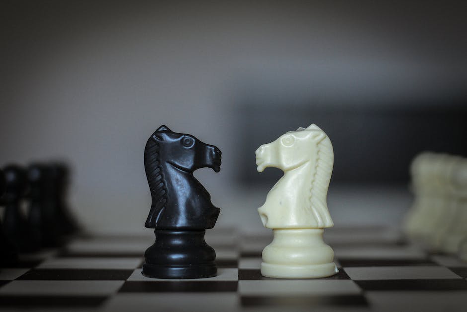 Two players sitting on a table for a chess tournament with a chessboard in front of them.