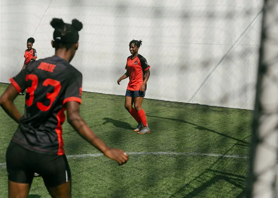 A group of women football players playing on a green field in a stadium, representing the growth and development of women's football leagues worldwide.